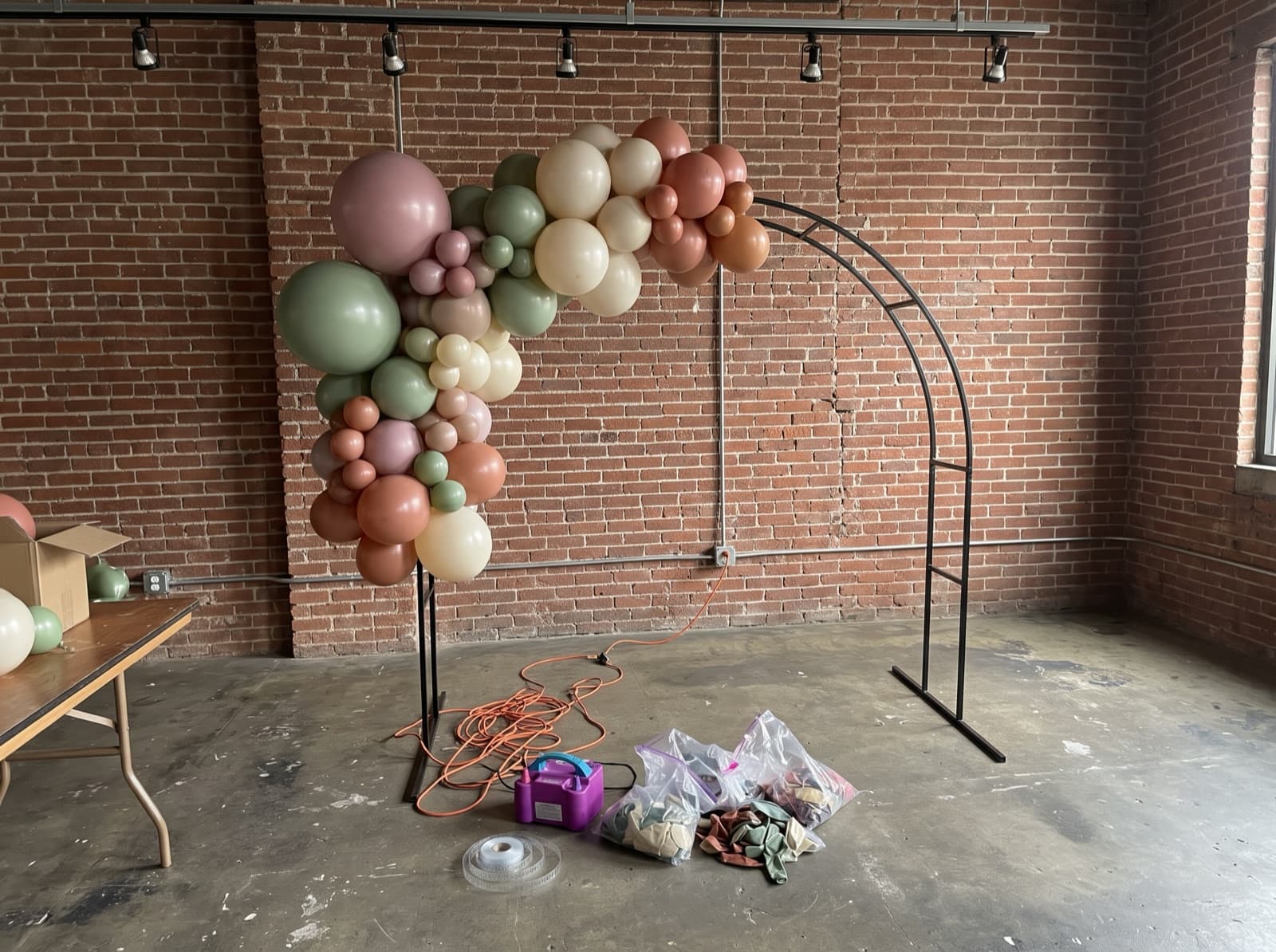 Organic balloon garland half-built on an arch frame before an event