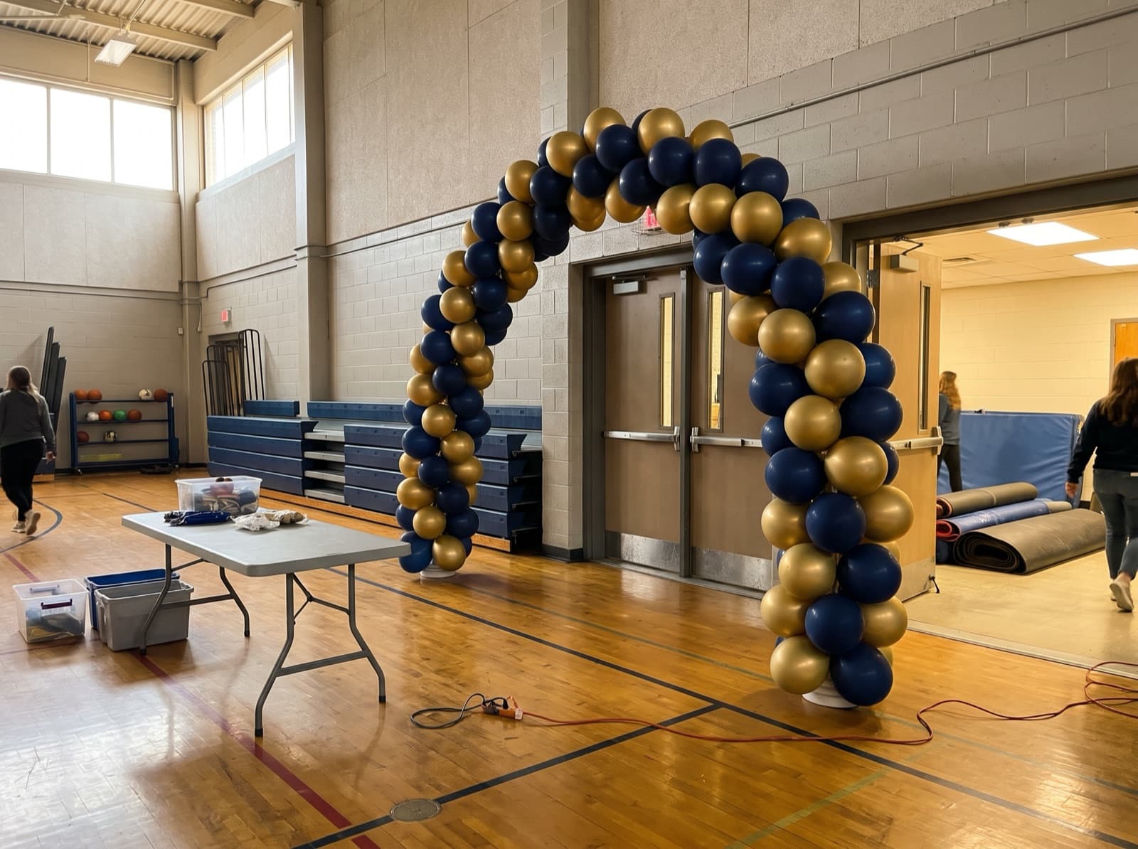 Spiral balloon arch in navy and gold over a school gym entrance