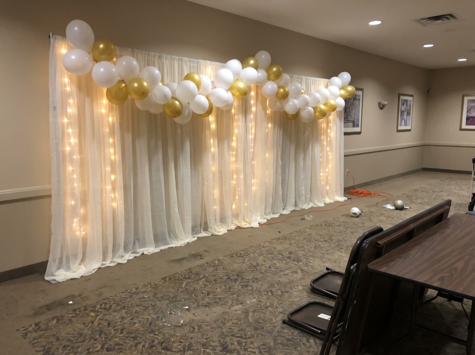 Draped backdrop with balloons and warm lights