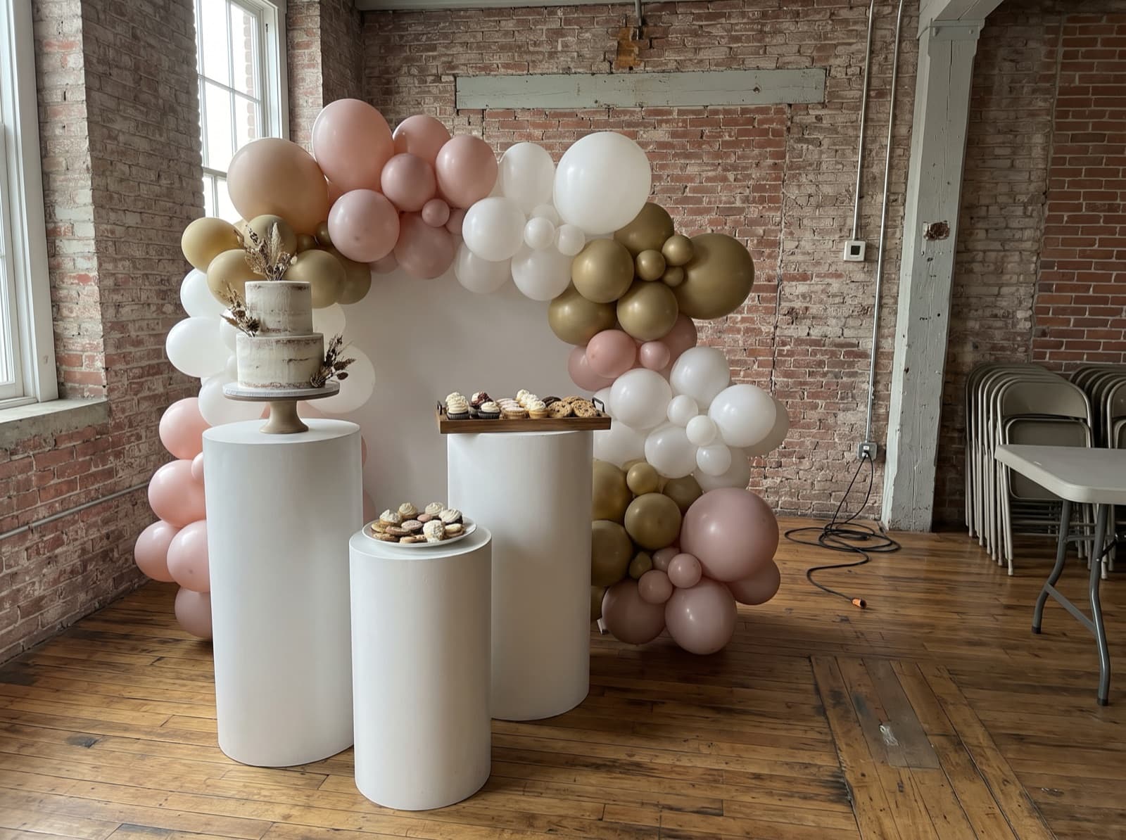Balloon backdrop with pedestals and a cake