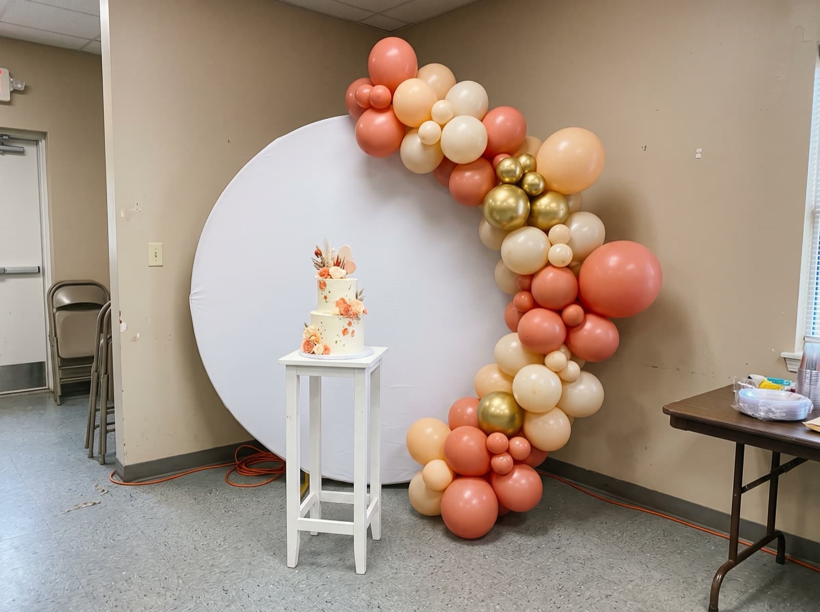 Round backdrop with a coral and gold organic balloon garland