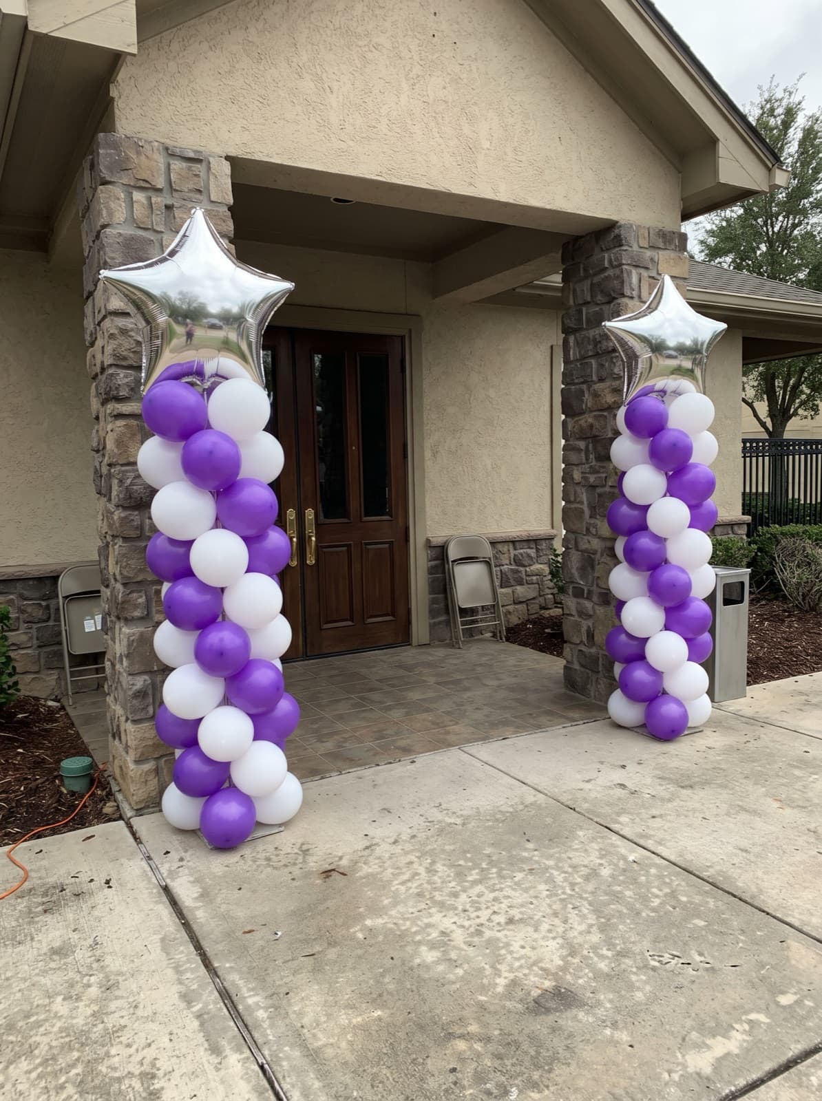 Purple and white balloon columns with silver star toppers for a graduation