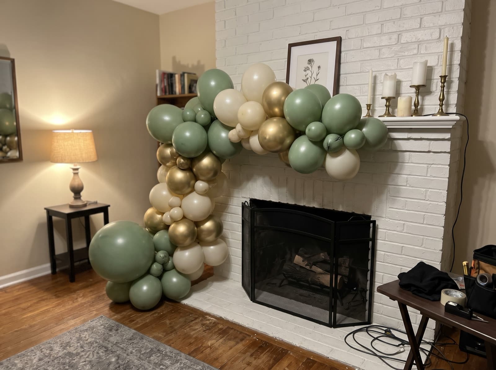 Organic balloon garland in sage, cream and brushed gold across a painted brick fireplace mantel in a Charlotte home