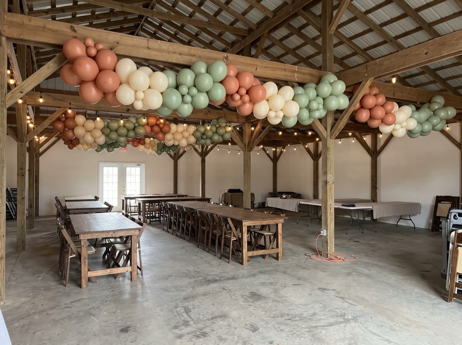 Hanging balloon garland canopy over barn dining tables