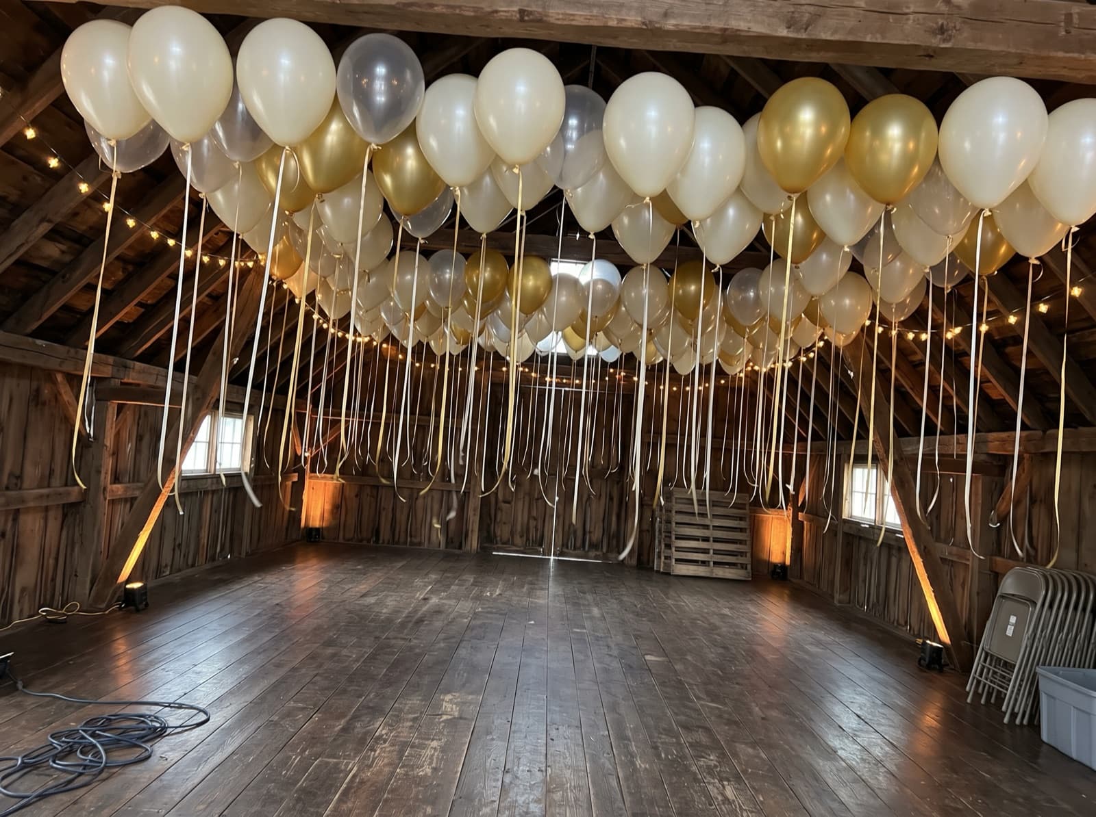 Balloon ceiling of ivory, clear and gold balloons over a dance floor in a Charlotte barn venue